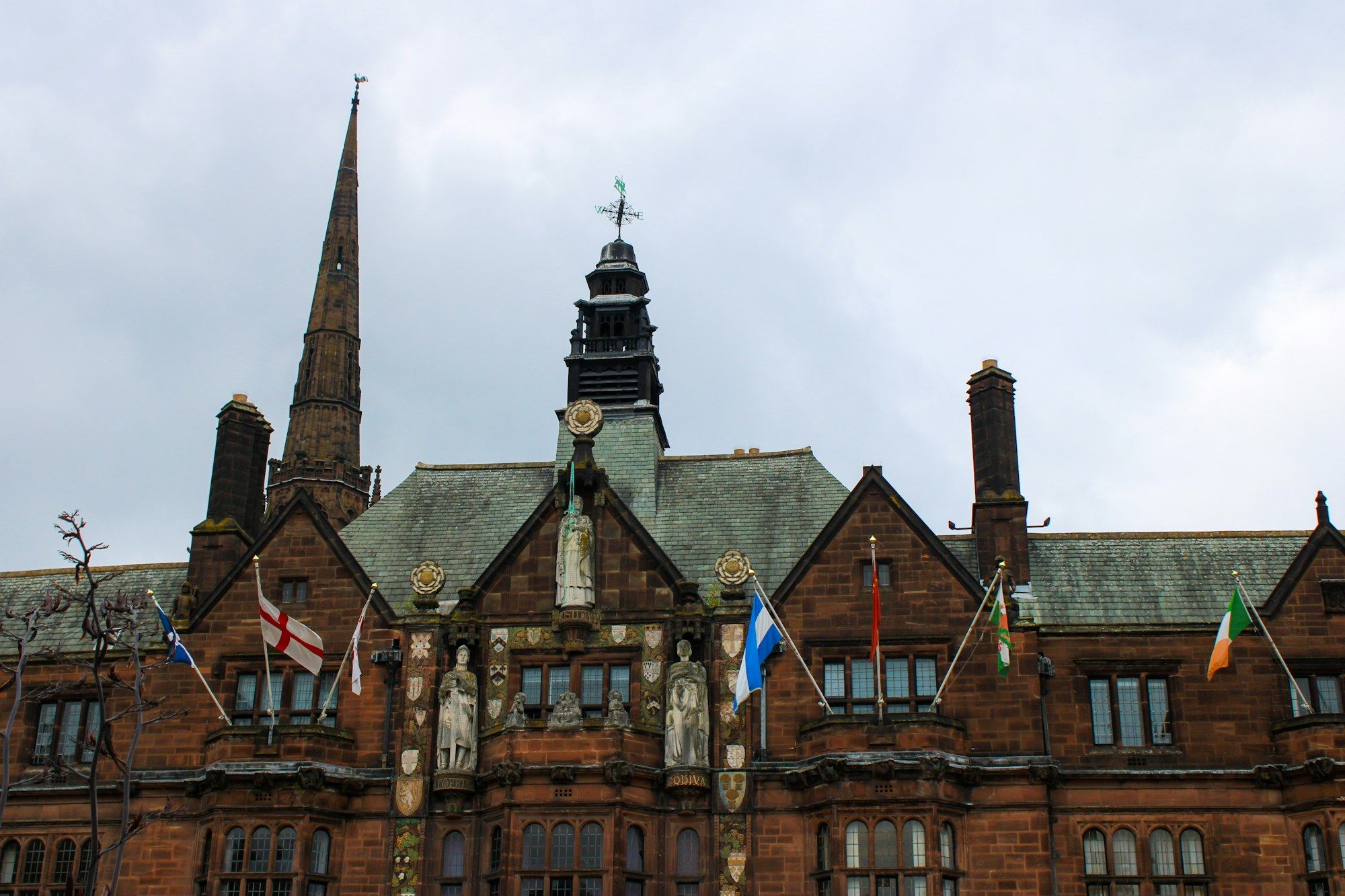 A red sandstone civic building in Coventry city centre with flags flying